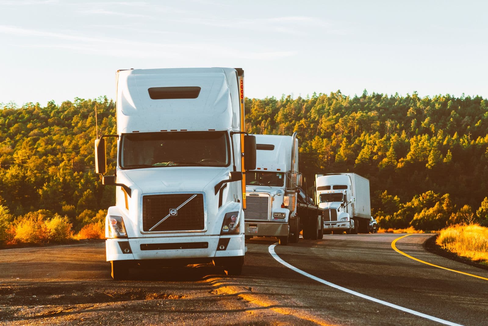 Freight Nova dry van semi-trucks on the open highway at golden hour